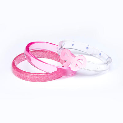 Set of three acrylic bangles. One is clear pink, one is glitter pink and another one is clear adorned with a pink bow. 