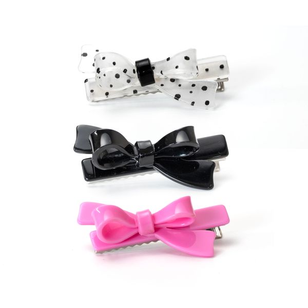 A set of three hair clips in pink, black, and white with polka dots design, displayed against a white background.