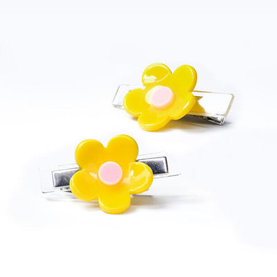 Pair of metal based hair clips each adorned with a yellow and light pink flower. 