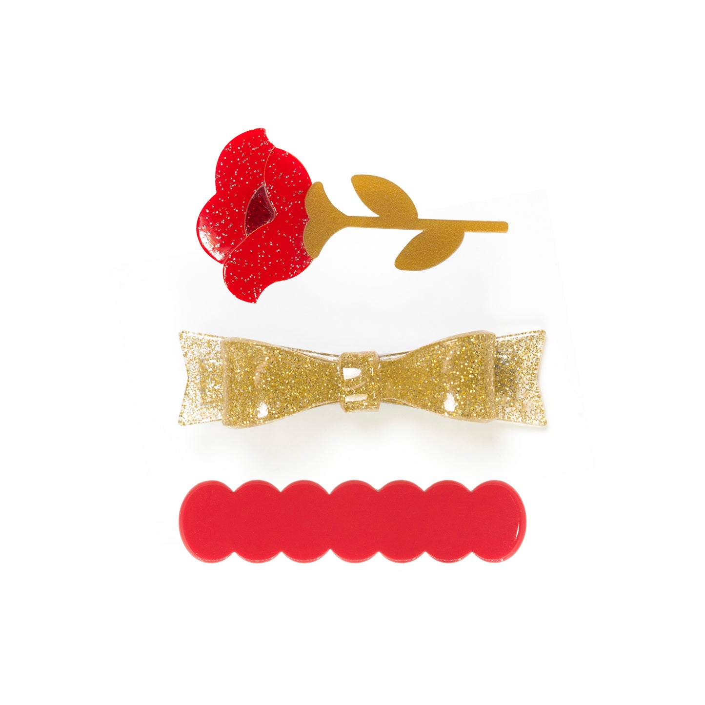 Trio of hair clips. One of them is adorned with a red rose, the second one is a gold glitter bow, and the third one is a simple red cutout. 