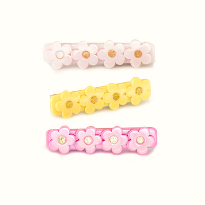 Trio of hair clips. All adorned with four flowers but in different colors. The first one is pink, the second one is nude and the third one is yellow