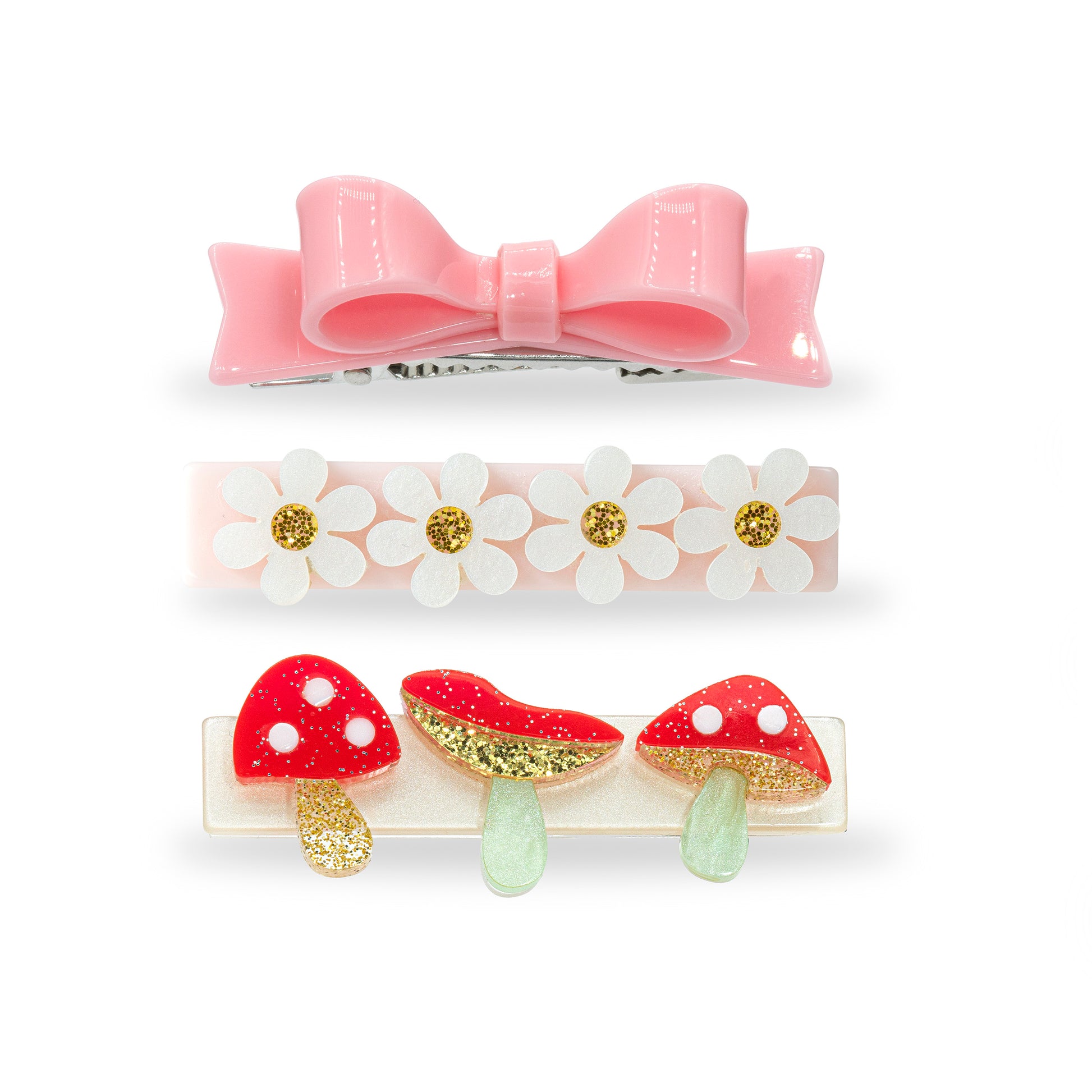 Trio of hair clips. One of them is adorned with a light pink statement bow. The second one has four daisies. And the third one has three red and gold glitter mushrooms. 