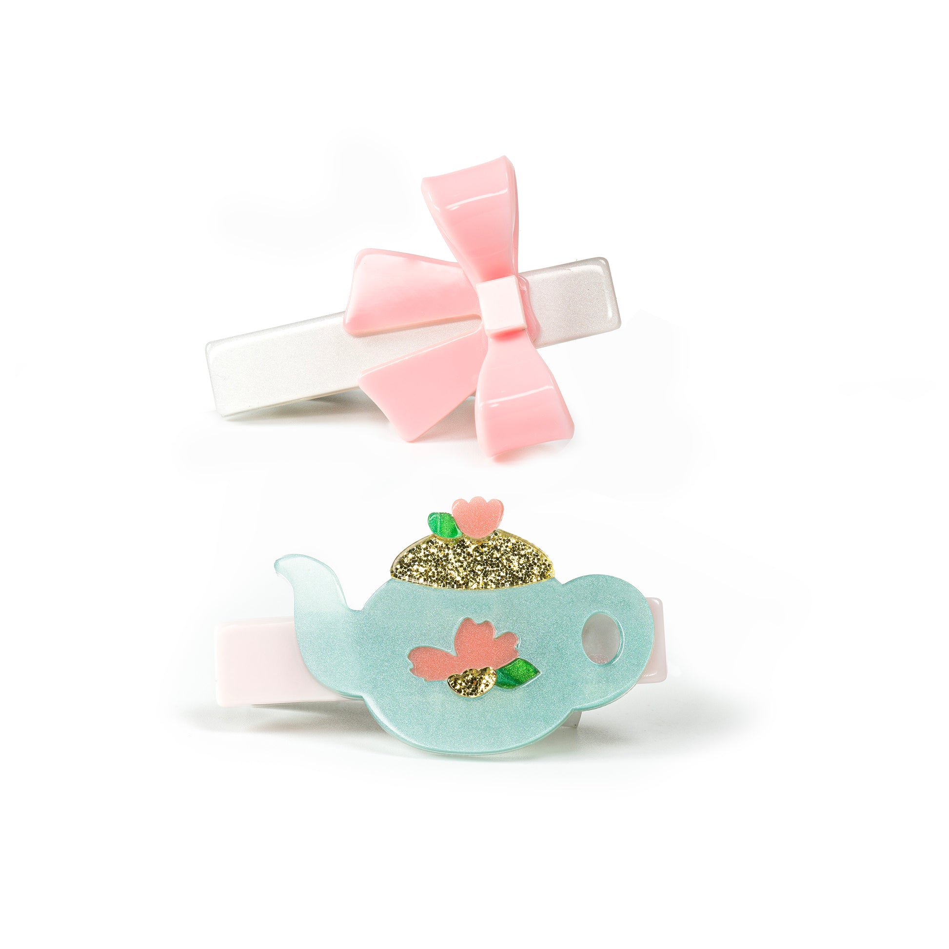 Pair of hair clips. One is adorned with a light pink bow and the other one with a glittery gold and mint teapot.