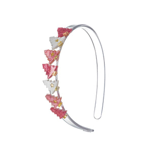 Clear acrylic headband adorned with seven small Christmas trees in different shades of pink.