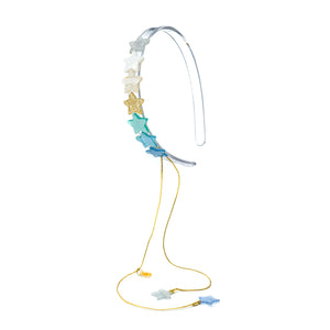 Clear acrylic headband adorned with seven small stars in different shades of blue, green, gold, white and silver. It also has two stars hanging from gold strings. 